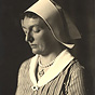 A White female nurse, turned slightly to her right and looking down.