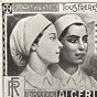 A White female nurse and a Berber-Arab female nurse, stand in front of a hospital.