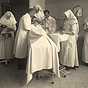 Two White male doctors and four White female nurses operating on a patient in a hospital.