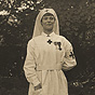 White female nurse in white wearing war medals and looking slightly to the right.