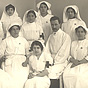 Group of nine White nurses and a White doctor in white uniforms.