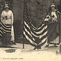 Two White female nurses in white stand and hold American flags at a tomb.