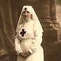 A White female nurse in white stands and looks slightly off to the right.