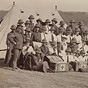 A group of White men and women wearing military uniforms and nursing uniforms in front of a tent.