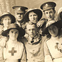 Five White female nurses in white stand for a photograph with three White male soldiers.