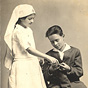 A White girl in white nursing uniform touches a sock that a White boy holds.