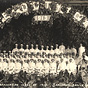 Large group of White male and female nurses in white sitting and standing for a group photo.