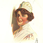A White female nurse in white, visible from chest up, smiling at viewer.