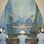 Three White female nurses in blue kneel and pray in a church.