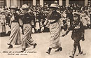 Three White female nurses in military uniforms march with White boy wearing military uniform.