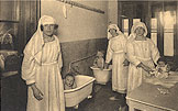 Three White female nurses tend to three White babies, two of which are in tubs.
