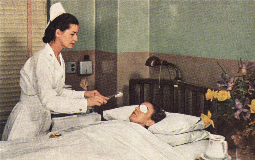 White female nurse treating a White female eye patient, lying in bed.