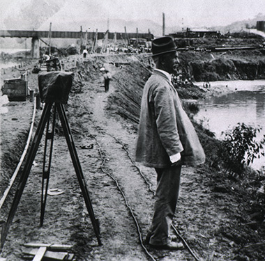 A photograph of a white man looking at a body of water at a construction site