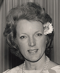 Dr. Tenley E. Albright, a White female wearing a pearl necklace and a flower in her hair.
