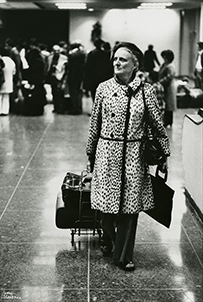 Dr. Mary Steichen Calderone, a White female in a long coat traveling with a suitcase and briefcase.