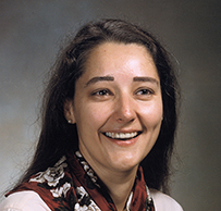 Dr. Patricia StandTal Clarke, a young, smiling American Indian woman posing for her portrait.