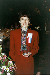 Dr. Ruth E. Dayhoff, a White female in a red suit jacket and skirt holding an award. 