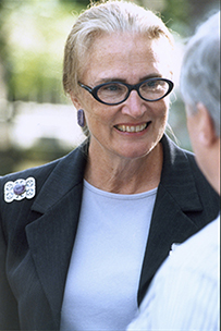 Dr. Mary Jane England, a White female with glasses in a suit smiling and looking across towards another person.