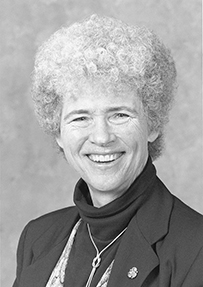 Dr. Faith Thayer Fitzgerald, a White female with curly short hair smiling for her portrait.