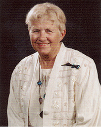 Dr. Jean L. Fourcroy, a White female wearing a white sweater and ribbon pin smiling for her portrait.