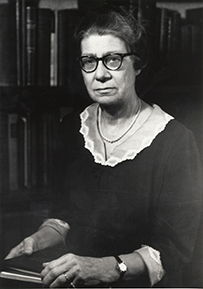 Dr. Virginia Kneeland Frantz, a White female in a dark blouse and glasses posing in front of a bookshelf.