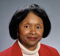Dr. Maxine Hayes, a smiling African American female wearing a red suit jacket and cream blouse posing for her portrait.