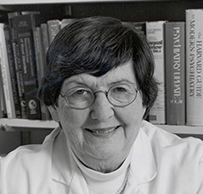 Dr. Jimmie C. Holland, a White female in a lab coat seated in front of bookshelves.