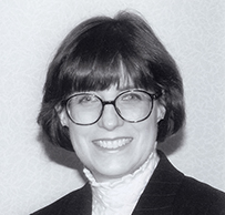 Dr. Christie Ann Huddleston, a smiling White female with glasses in a dark jacket posing for her portrait.
