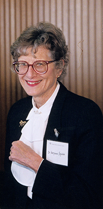 Dr. Georgiana Mary Jagiello, a White female in a dark jacket and ruffle blouse with a nametag.