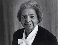 Dr. Grace Marilynn James, an elderly African American female in a dark jacket and white bow blouse.