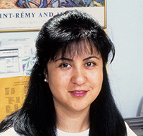 Dr. Nancy E. Jasso, a female with dark hair writing at a desk in an office.