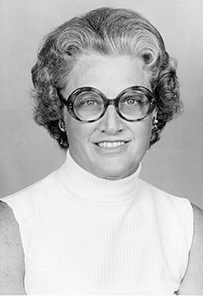Dr. Carol Johnson Johns, a female with short curly hair and glasses posing for her portrait.