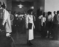 Dr. Edith Irby Jones, an African American female, in a suit, standing in the center of a hallway of the University of Arkansas Medical School, 1949.