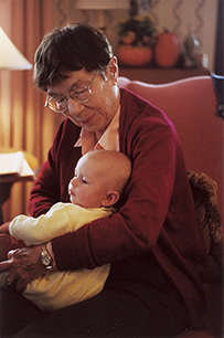 Dr. Mary Elizabeth Dickason King, an elderly woman holding a baby in her arms while seated indoors.