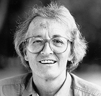 Dr. Elisabeth Kübler-Ross, a White female wearing round glasses smiling for her portrait outdoors.