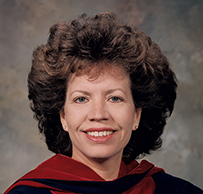 Dr. Yvette Laclaustra, a female in a red and black graduation gown posing for her portrait.