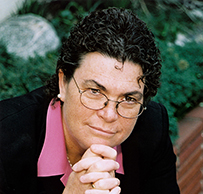 Dr. Susan M. Love, a White female with dark curly hair in a pink blouse and suit jacket posing for her portrait.
