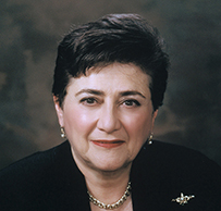Dr. Carol Cooperman Nadelson, a White female in a dark suit posing in a chair for her portrait.