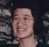 Dr. Ina Park Rhee, a smiling Asian female wearing a cap and gown outdoors.