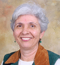 Dr. Cecilia M. Romero, a White female with short hair in a green vest posing for her portrait.