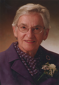 Dr. Louise Schnaufer, an elderly White female with glasses in a purple blouse and rose boutonniere. 