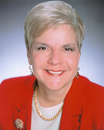 Dr. Paula L. Stillman, a White female in a red suit smiling for her portrait.