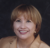 Dr. Adela S. Valdez, a female in professional attire, smiling for her portrait.