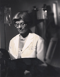 Dr. Mary Lake Polan, a white female in a lab coat looking down at a folder in a room with an IV.