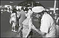 A PHS officer examines a smallpox vaccination take on the arm of a woman at a checkpoint for Cuban refugees at Port Everglades, Florida.