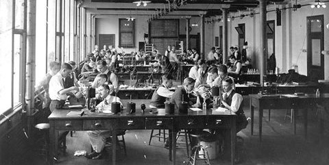 Black and white photograph of a pharmacology laboratory featuring students at various tables performing scientific experiments.