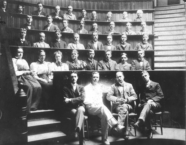 Black and white photograph of a group portrait of unidentified Johns Hopkins Medical School graduating class with (left to right) professors Harvey Cushing, Howard Kelly, Sir William Osler, and William S. Thayer seated in foreground.