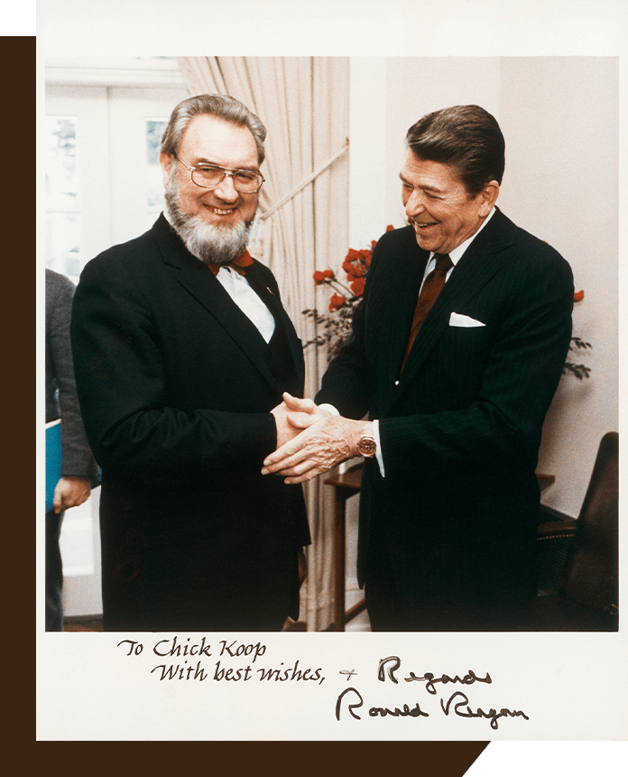 El Presidente Ronald Reagan (derecha) y el Dr. C. Everett Koop (izquierda) se estrechan la mano.