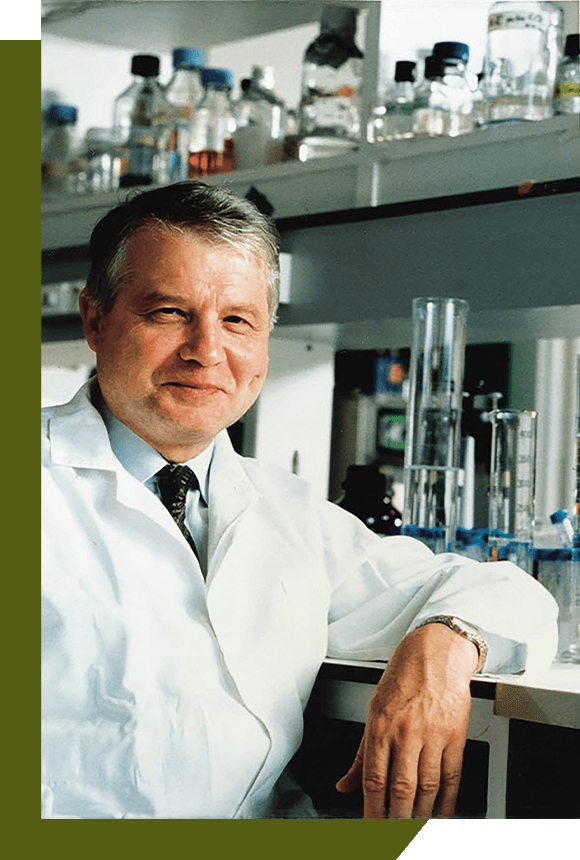 Dr. Luc Montagnier smiling and leaning on a lab table.