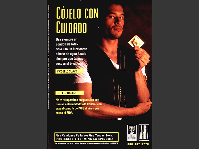 A Latino man stands holding a condom